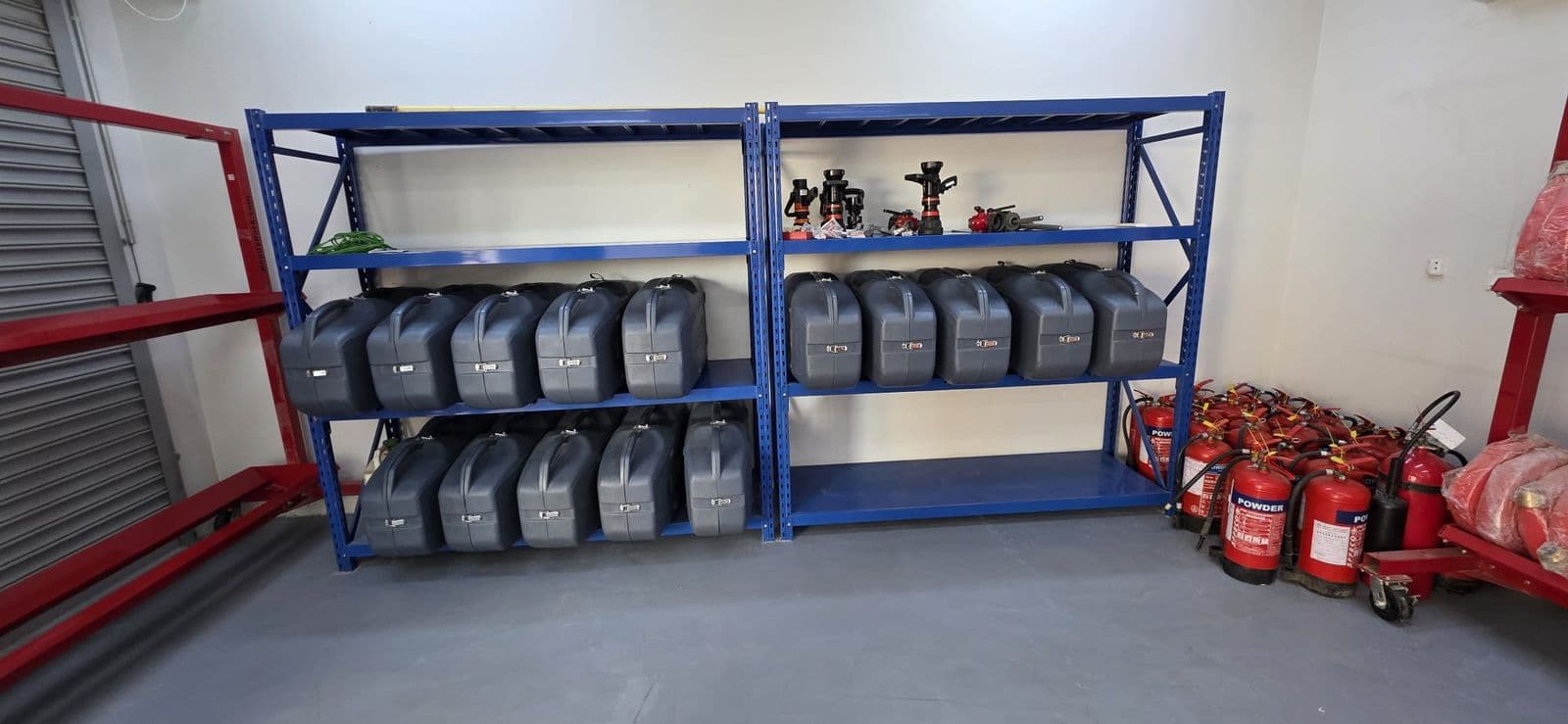 Breathing apparatus sets and cylinders racked on blue steel shelving.