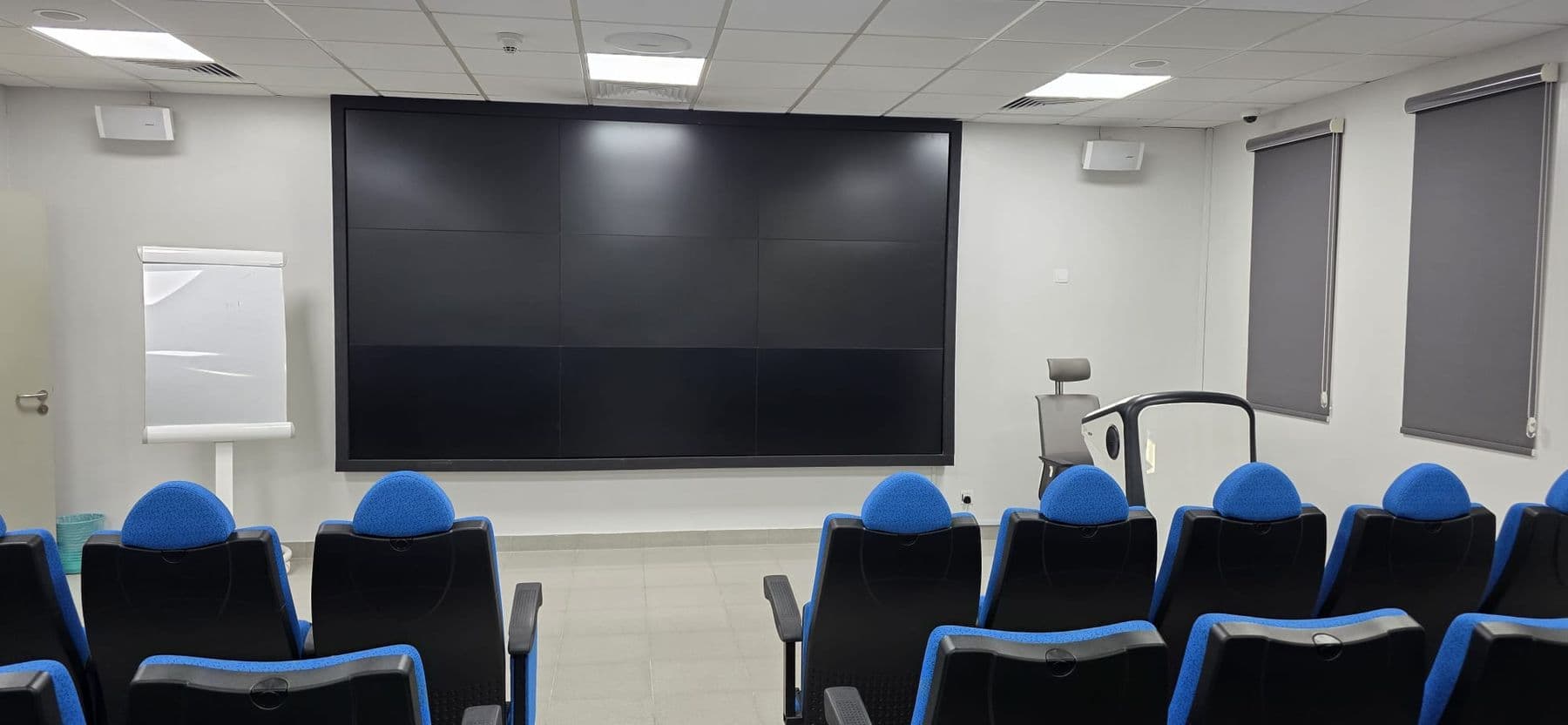 A classroom set out in rows facing a large wall-mounted display.