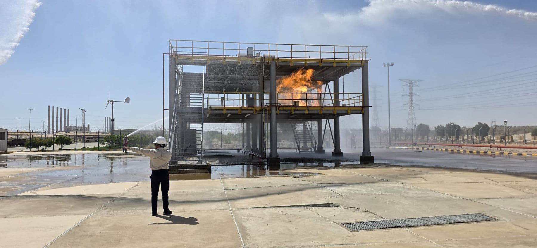 Flame spreading across the first-floor deck of the process rig, seen from the apron.