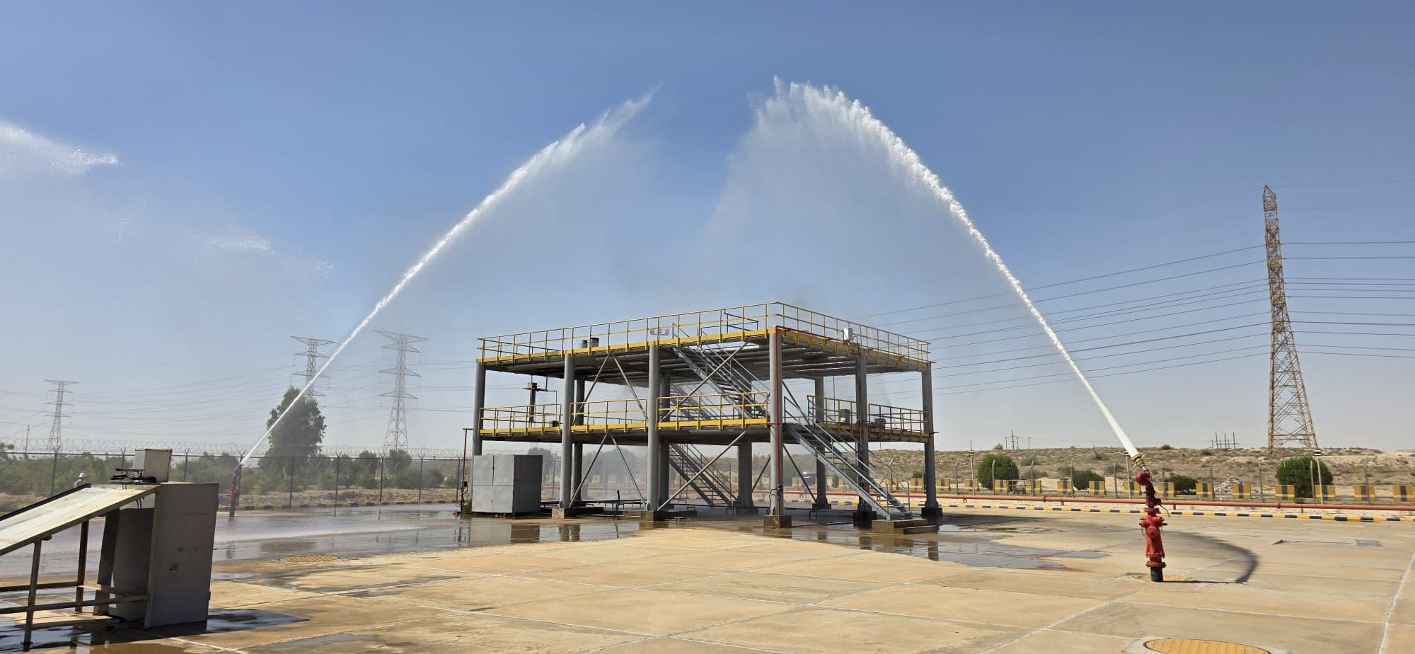 Two fixed water monitors throwing crossing arcs of water over the process rig.