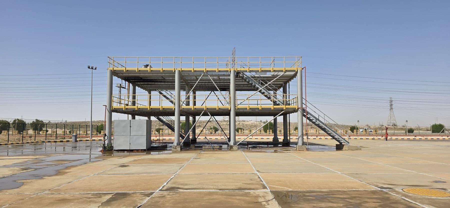 The two-storey steel process rig on the fire ground, unlit, with its access stairs and pipework visible.